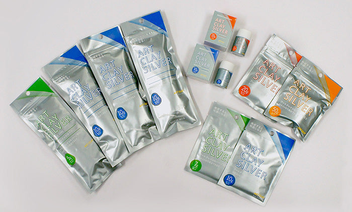 Silver packages of Art Clay Silver on a white background